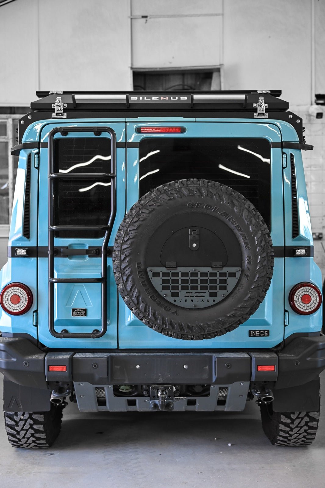 Grey molle panel on Buzz Overland Spare Wheel Storage Cubby for INEOS Grenadier, enhancing style and functionality for off-road adventures with 17-inch wheel compatibility.