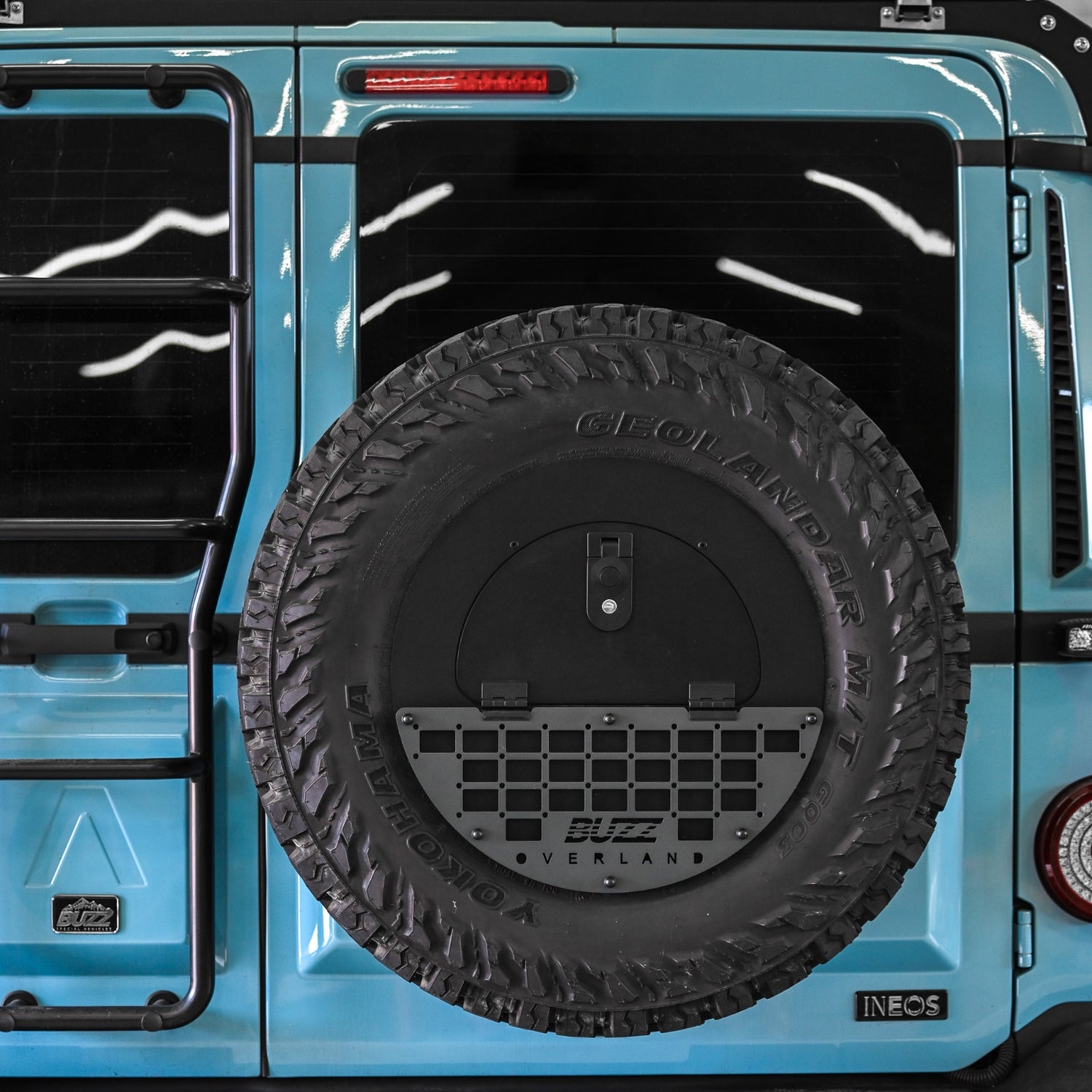 Grey molle panel on Buzz Overland Spare Wheel Storage Cubby for INEOS Grenadier, enhancing style and functionality for off-road adventures with 17-inch wheel compatibility.